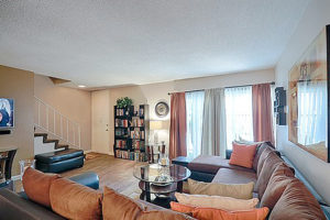 hardwood floor living room with couch, rug, decorations on wall, facing doorway, bookshelves