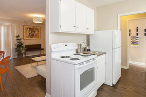 Affordable Apartments in Long Beach, CA - Seaport Village Apartments - Kitchen with White Cabinets, Light Countertops, Window, and White Appliances