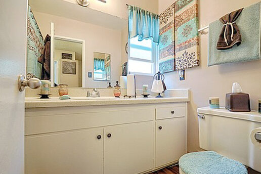 bathroom with white cabinets, mirror, blue accent decor